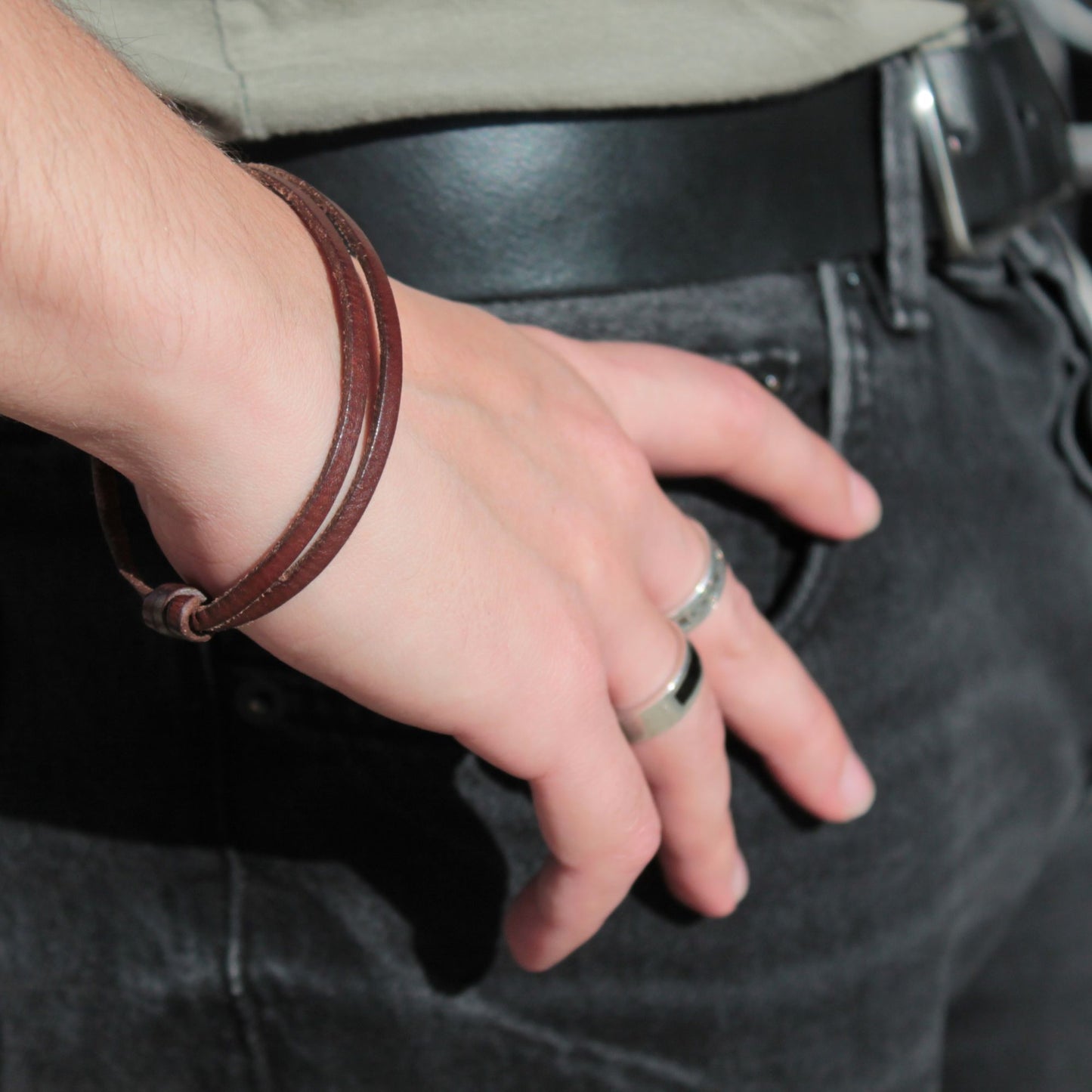 Pulsera de cuero TIRANT combinada con anillos de plata en mano masculina, estilo moderno y elegante