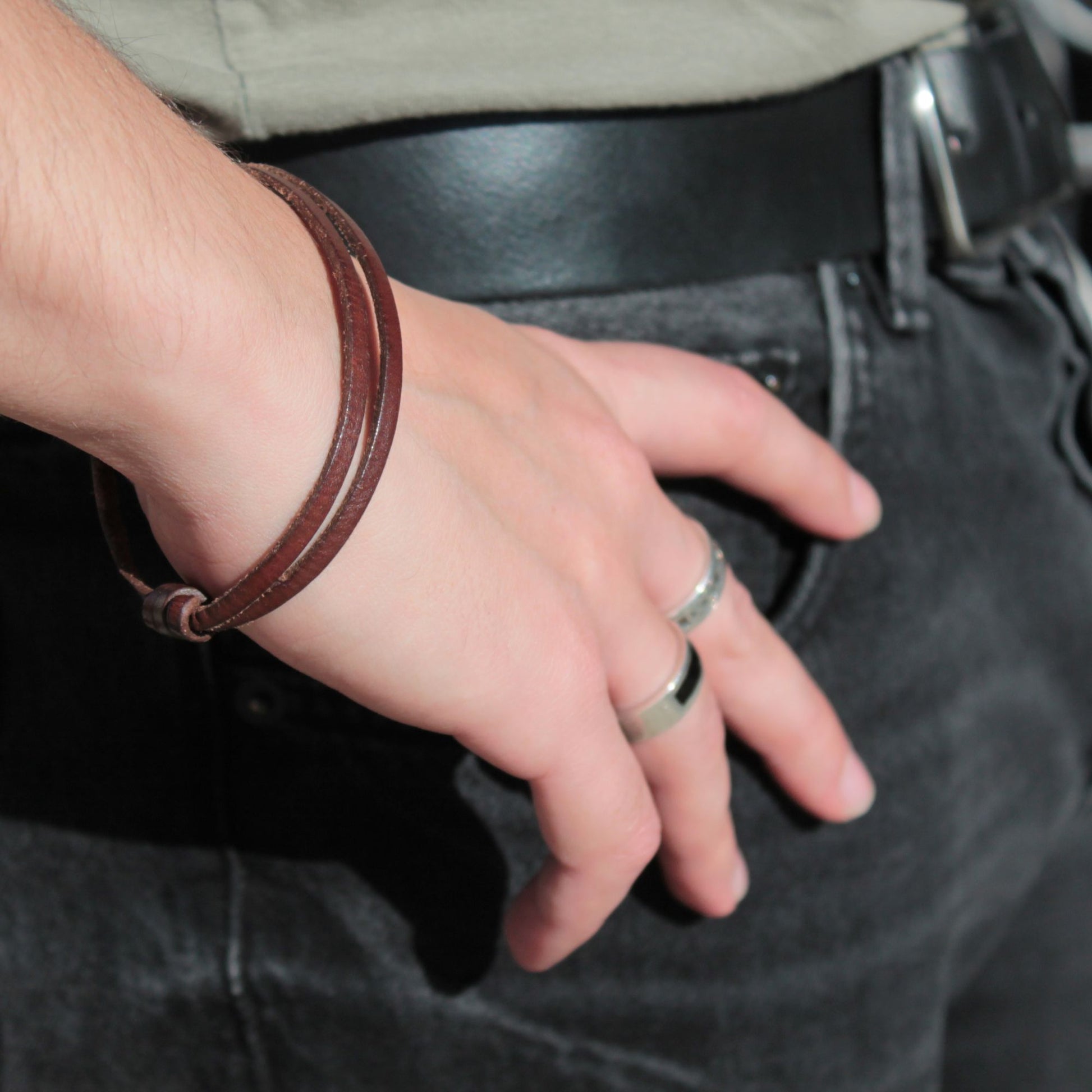 Pulsera de cuero TIRANT combinada con anillos de plata en mano masculina, estilo moderno y elegante